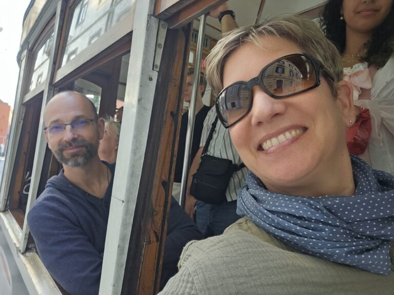 Bonnie und Jan sitzen in der Straßenbahn und grinsen in die Kamera